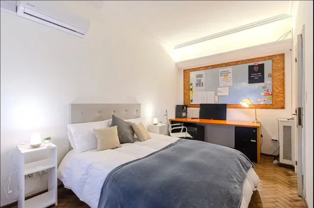 A double bed beside a desk and pinboard in the Office Room.