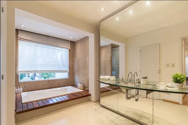 The Jacuzzi Suite bathroom, with a large tub by the window and a glass vanity.